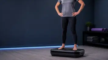 Person står med let bøjede knæ og bare fødder på vibrationsplade